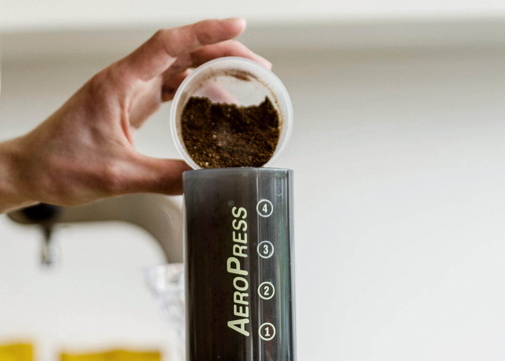 pouring coffee grinds into aeropress