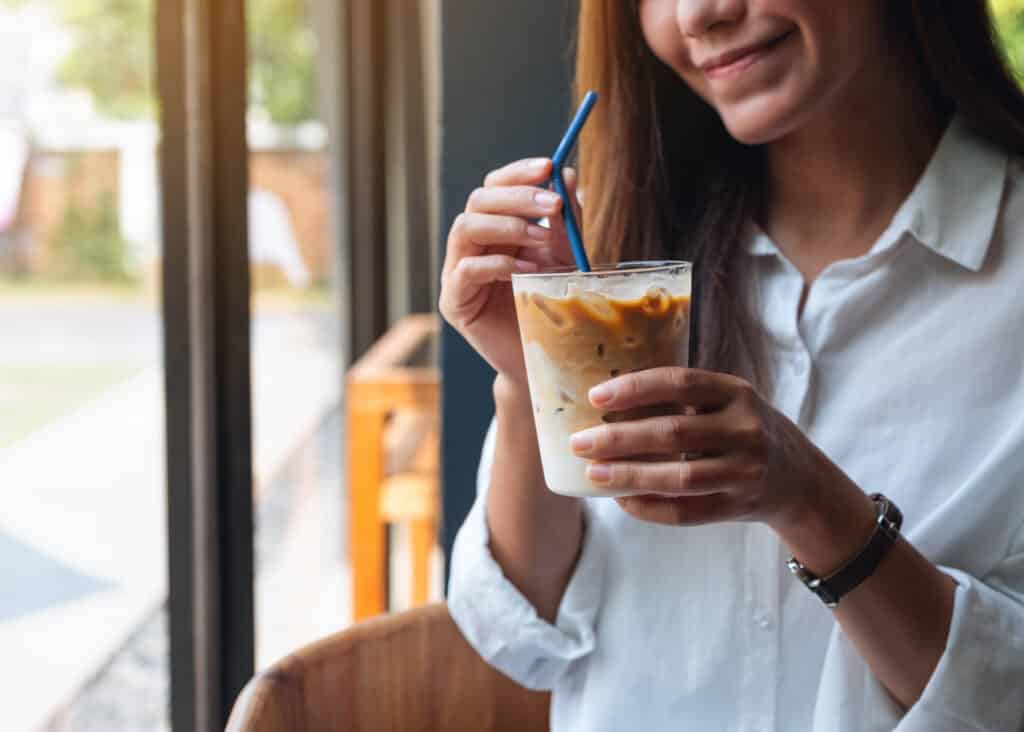woman drinking iced coffee with cream