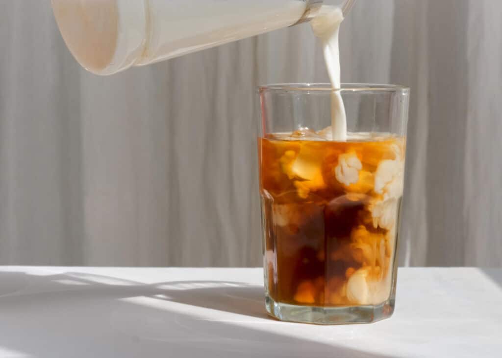 pouring milk into cold brew coffee