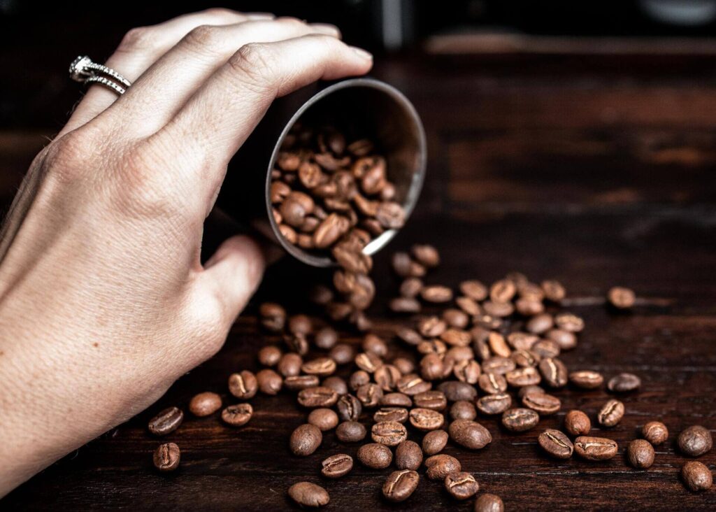 womans hand pouring coffee beans on a table