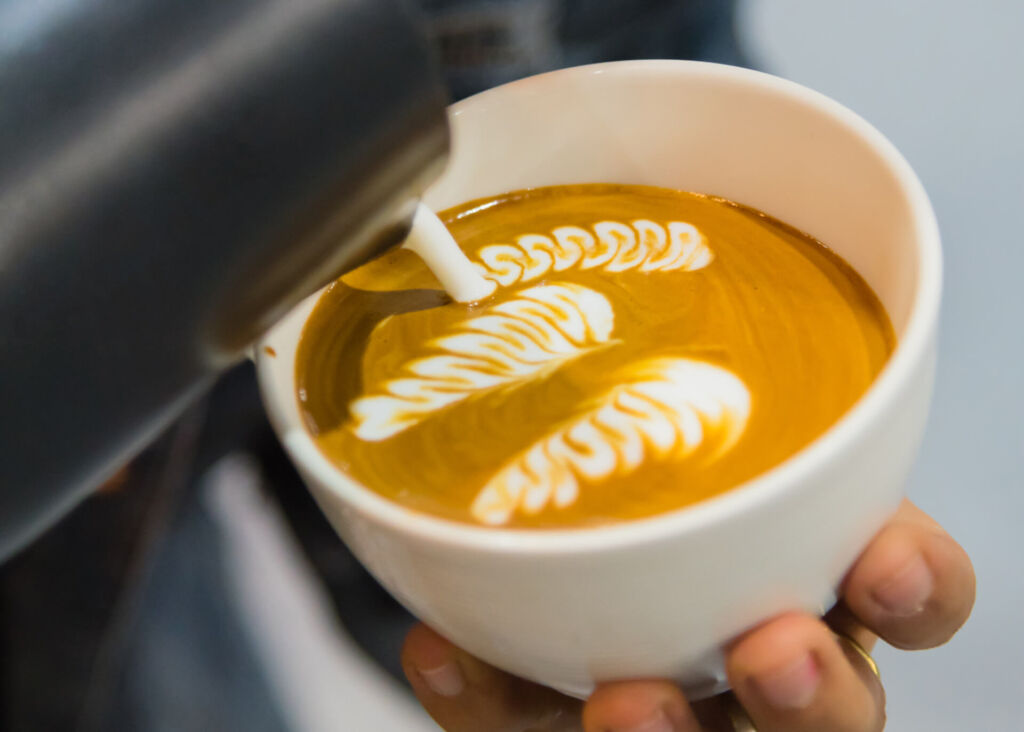 barista making latte art in a cup of coffee