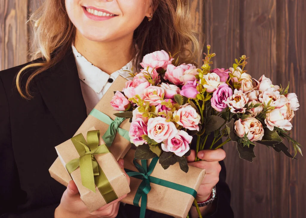 smiling teacher holding gifts and flowers