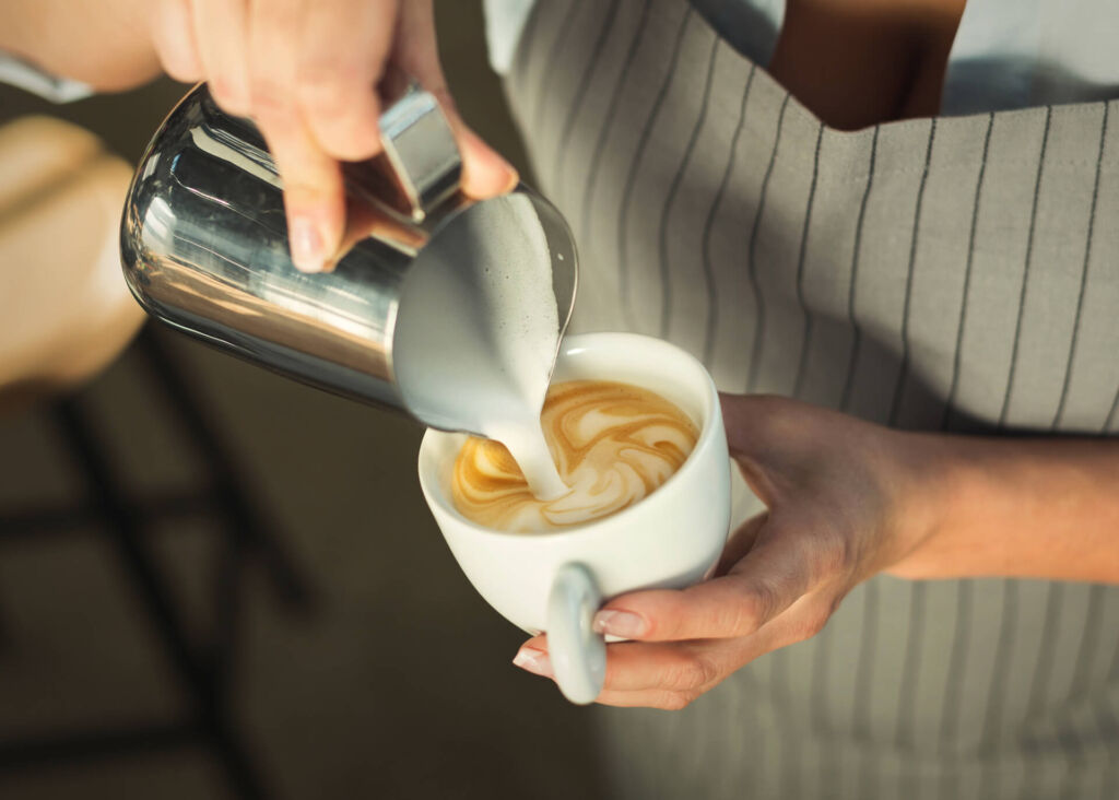 barista pouring milk into cappuccino