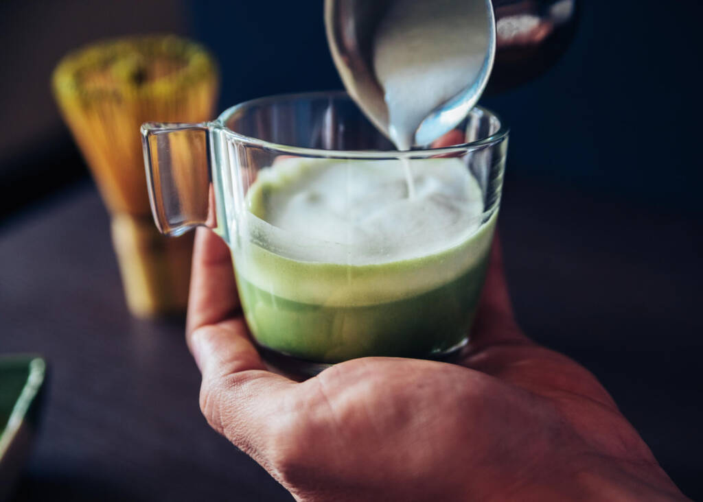 pouring steamed milk into matcha latte
