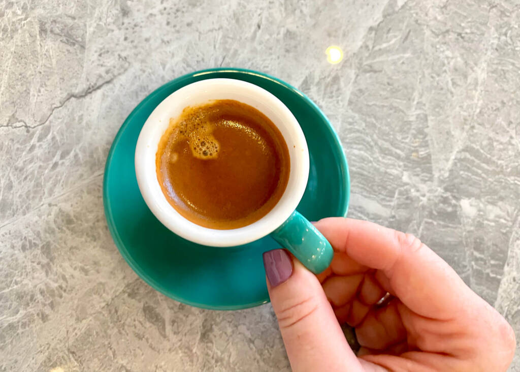 hand holding espresso cup with golden crema
