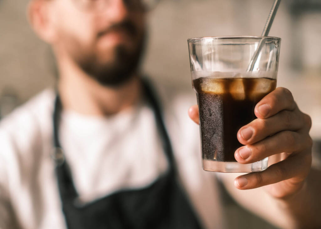 barista holding cold brew coffee glass