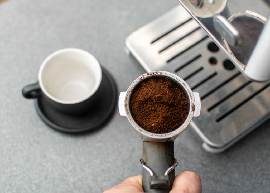 holding portafilter with ground coffee before making espresso