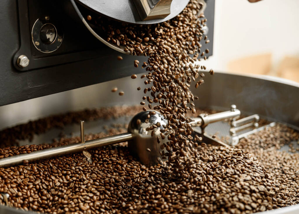 roasted coffee beans pouring out of roasting machine