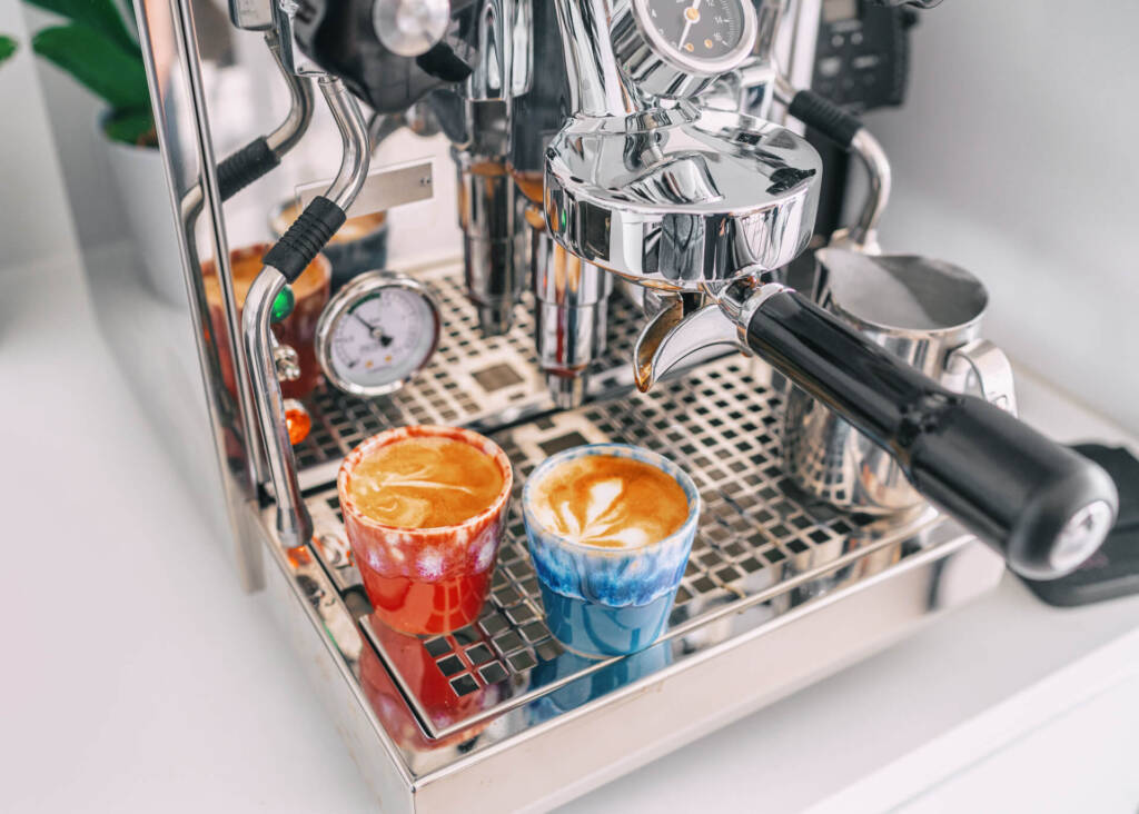 two cups of cortado on a drip tray of espresso machine